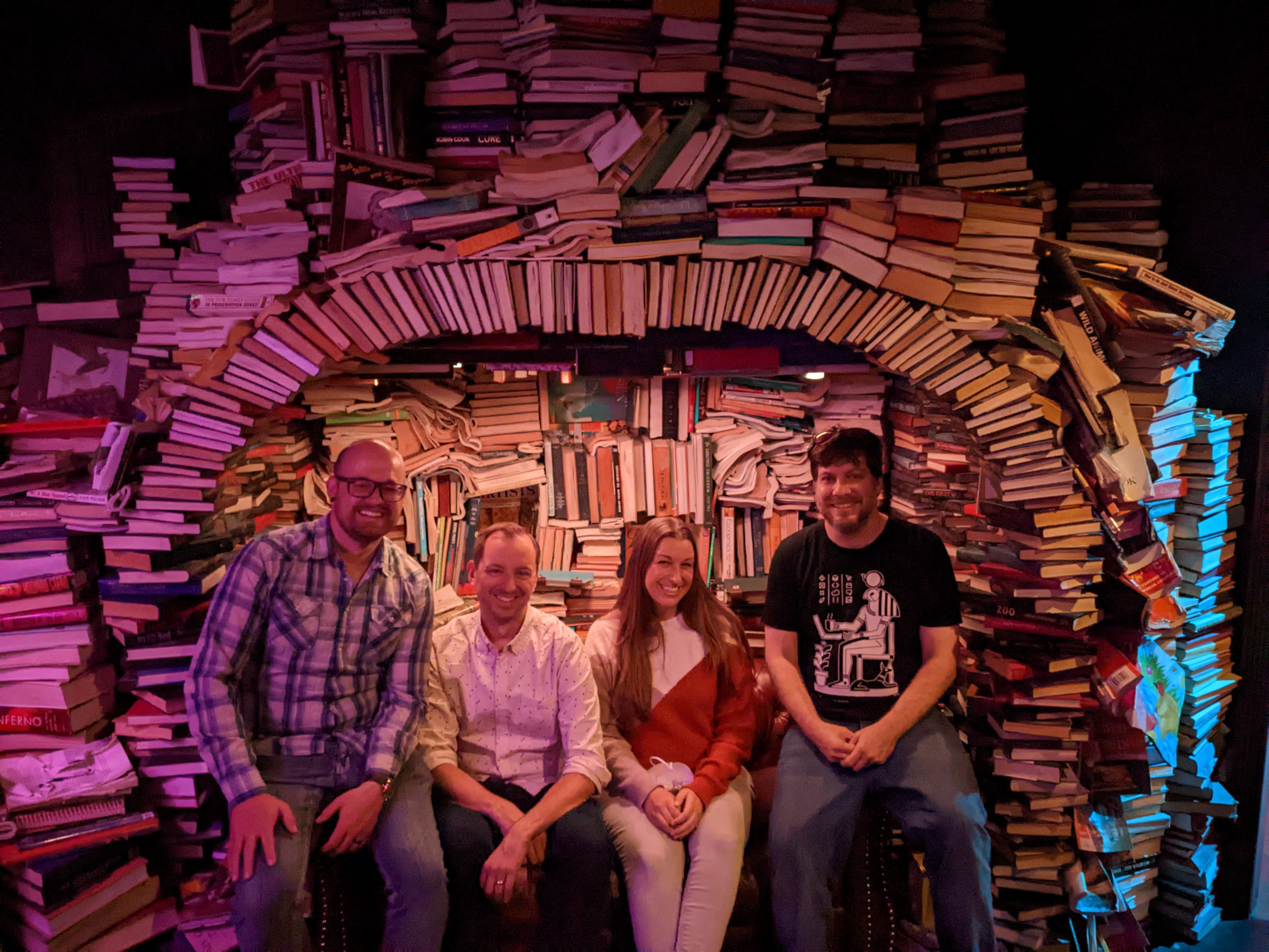 Four Aten staff in front of a book art sculpture at Meow Wolf